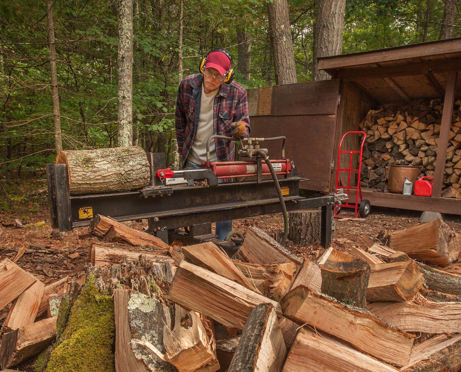 A man uses a wood splitter to process firewood.