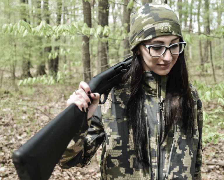 A turkey hunter carries a 20 gauge shotgun through the woods.