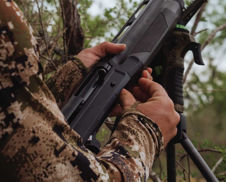 A turkey hunter loading his shotgun during a turkey hunt.