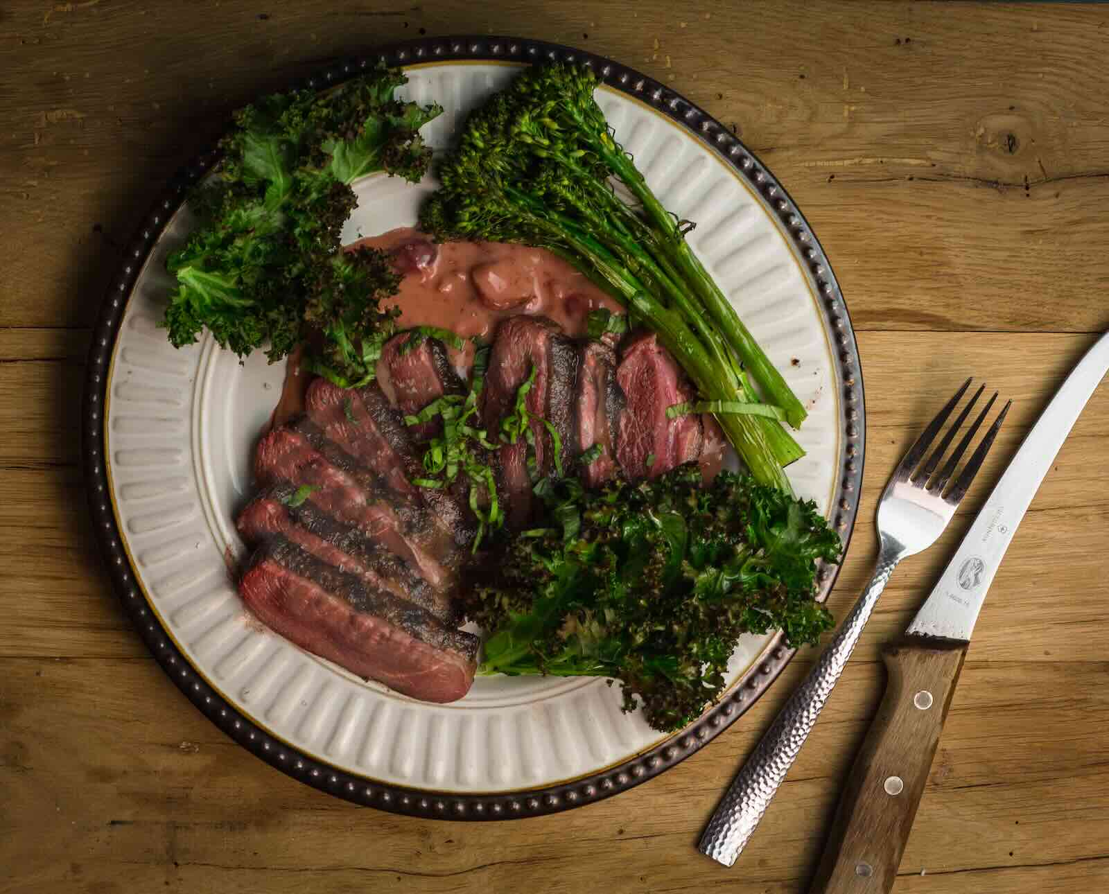 Sous vide cooked coose breast sliced on a plate with green garnish and a cherry sauce