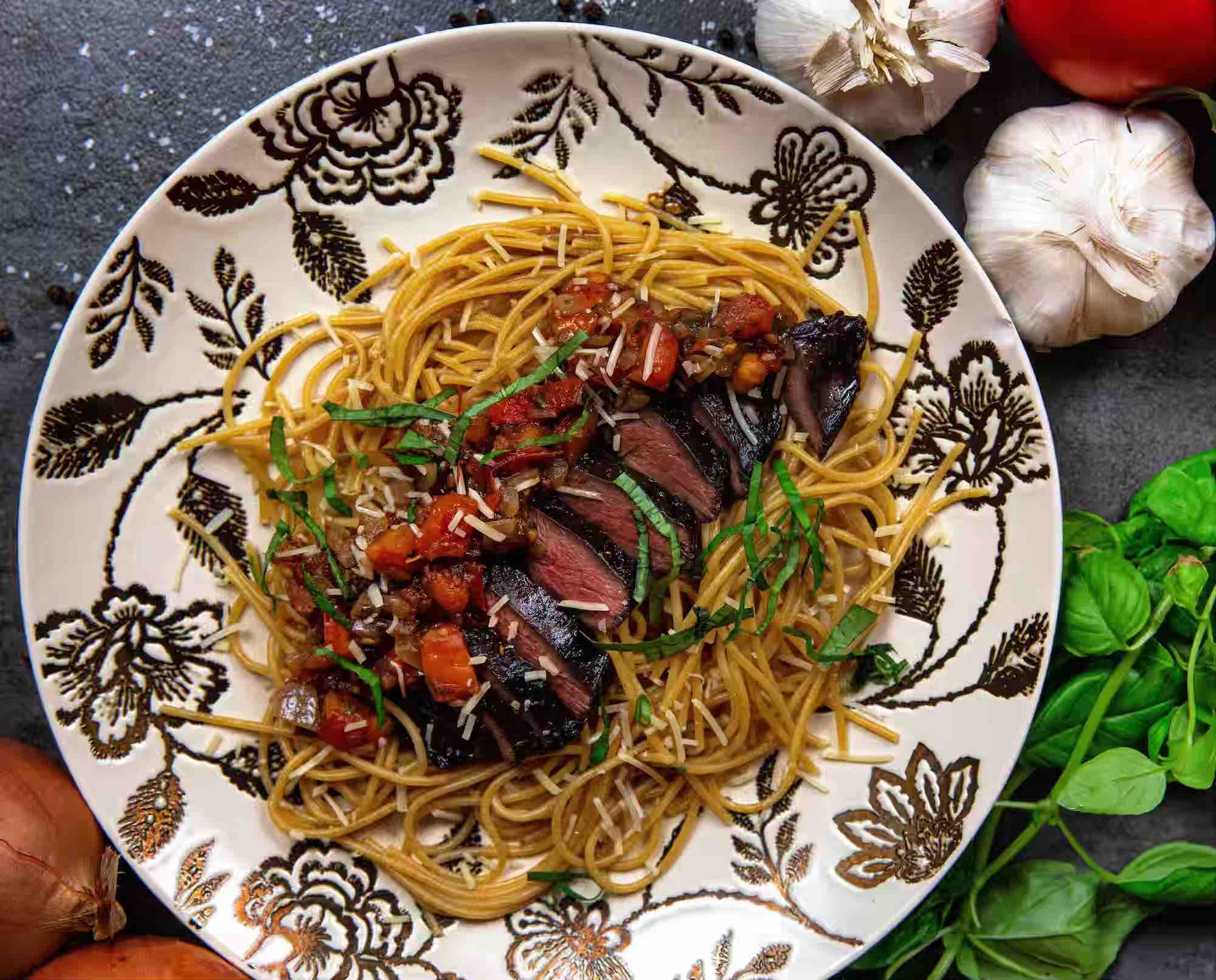 A plate of pomodoro topped with medium-rare prairie chicken breast with fresh ingredients in the background