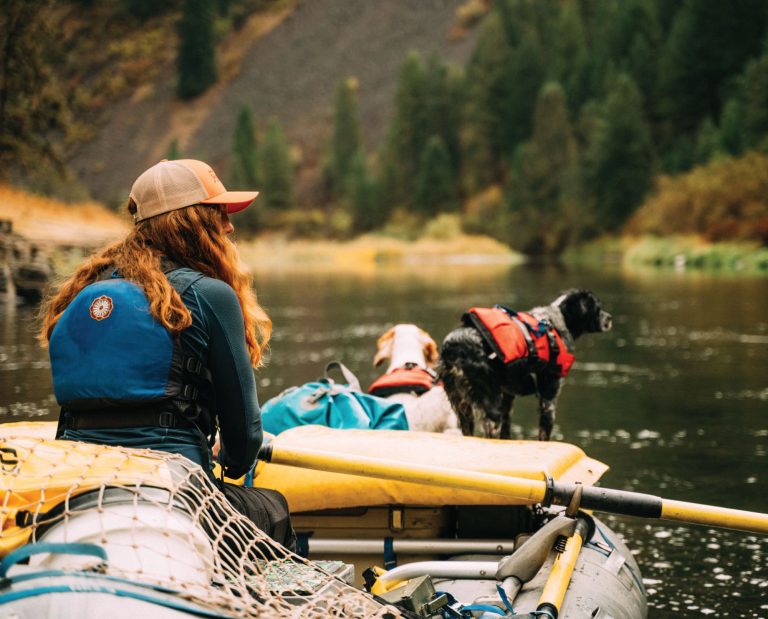 a woman rafts down a river with her bird dogs in pursuit of ruffed grouse.