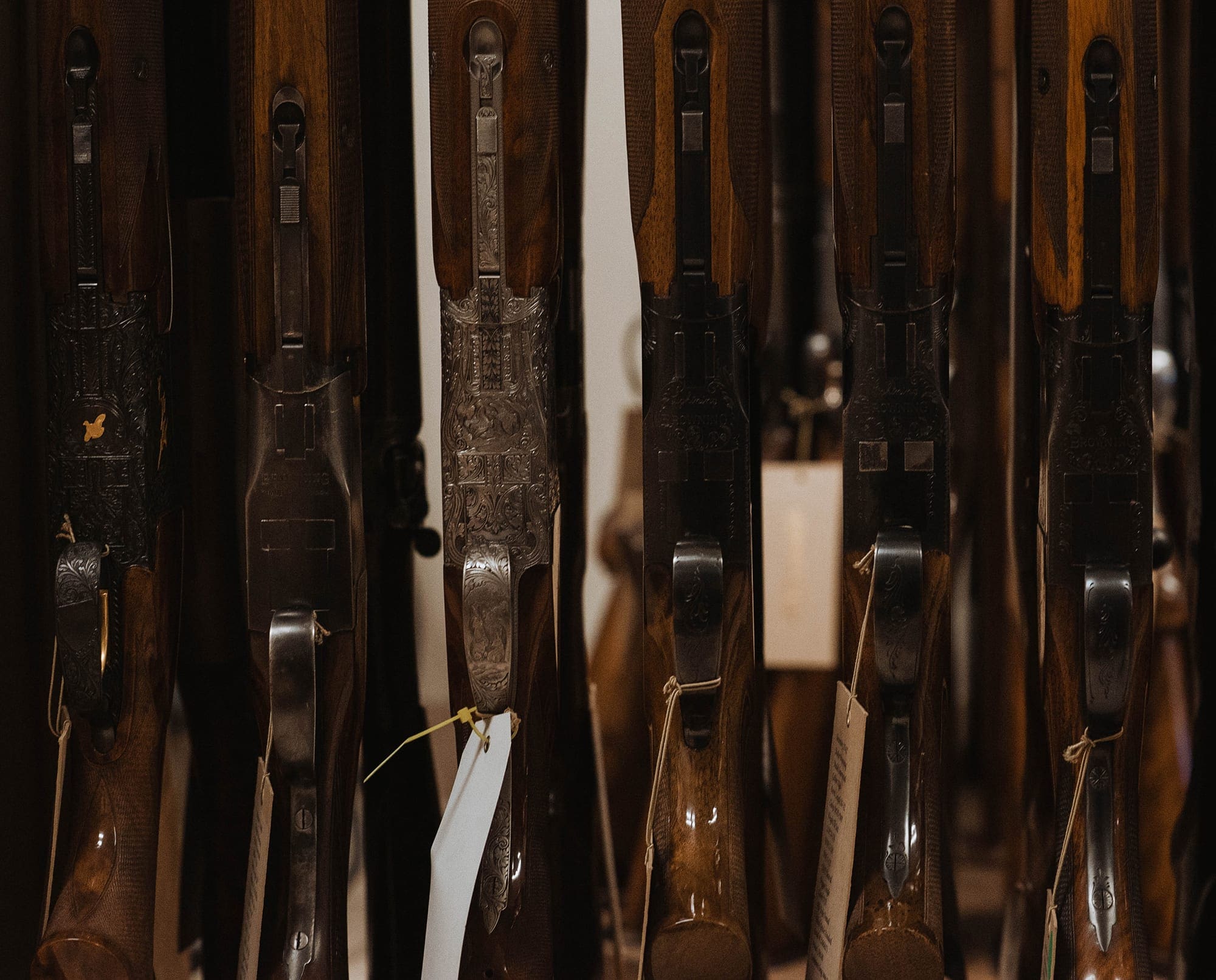 A set of over and under shotguns rest side by side on a store rack.