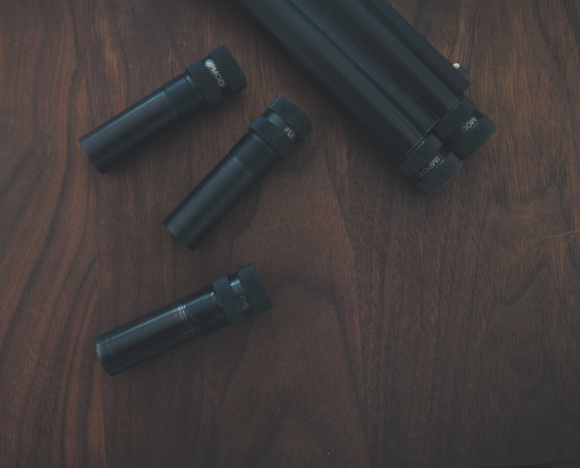 shotgun chokes on a table with an over and under shotgun.