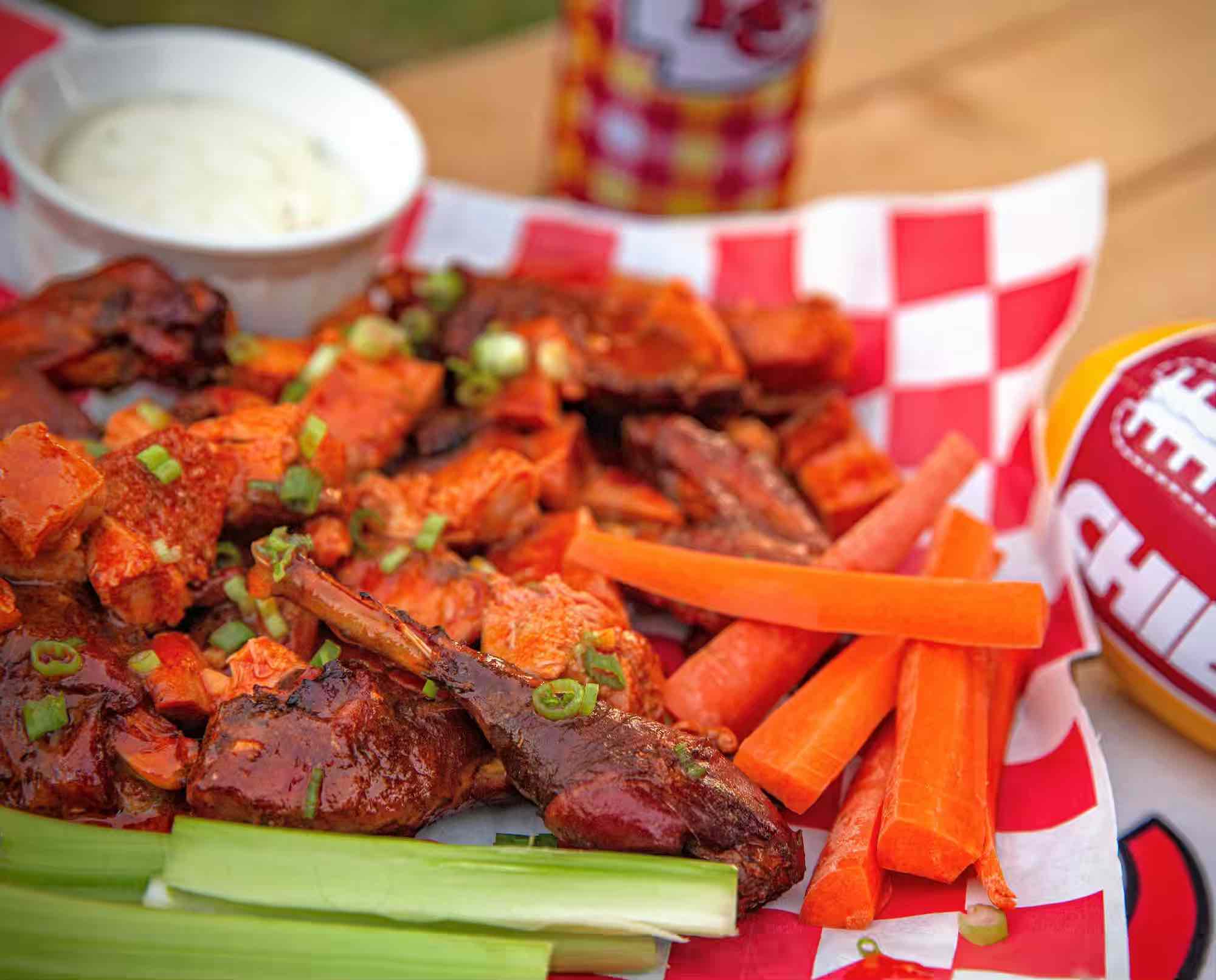 A plate of buffalo fried pheasant pieces with carrot and celery sticks and bleu cheese dip