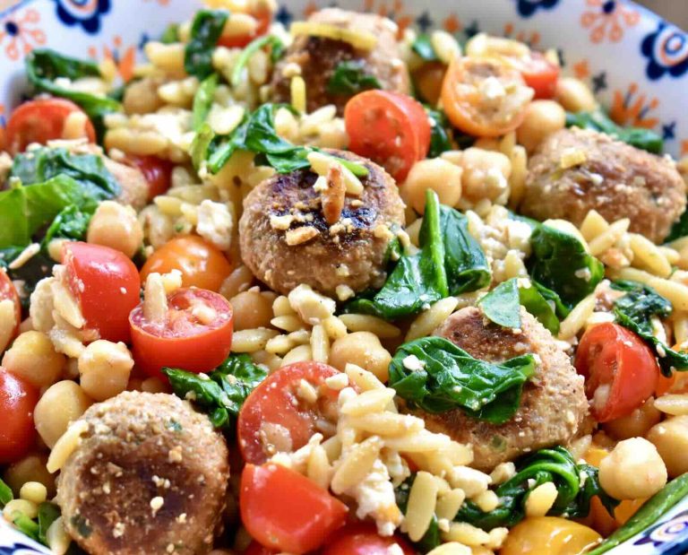 A colorful pasta salad with turkey meatballs, tomatoes, chickpeas, spinach, and orzo pasta.