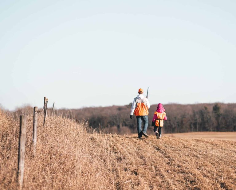 Two hunters walk through a harvested crop field in Ohio.
