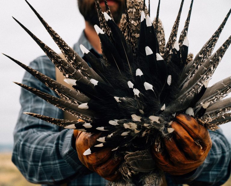 An upland hunter holds up a greater sage grouse.