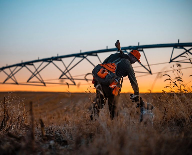 An upland hunter pets his bird dog while hunting near a corn field in Nebraska.