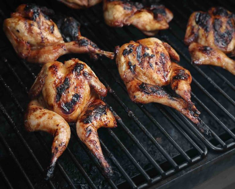 Spatchcocked quail coated in huli huli sauce, cooking on a grill