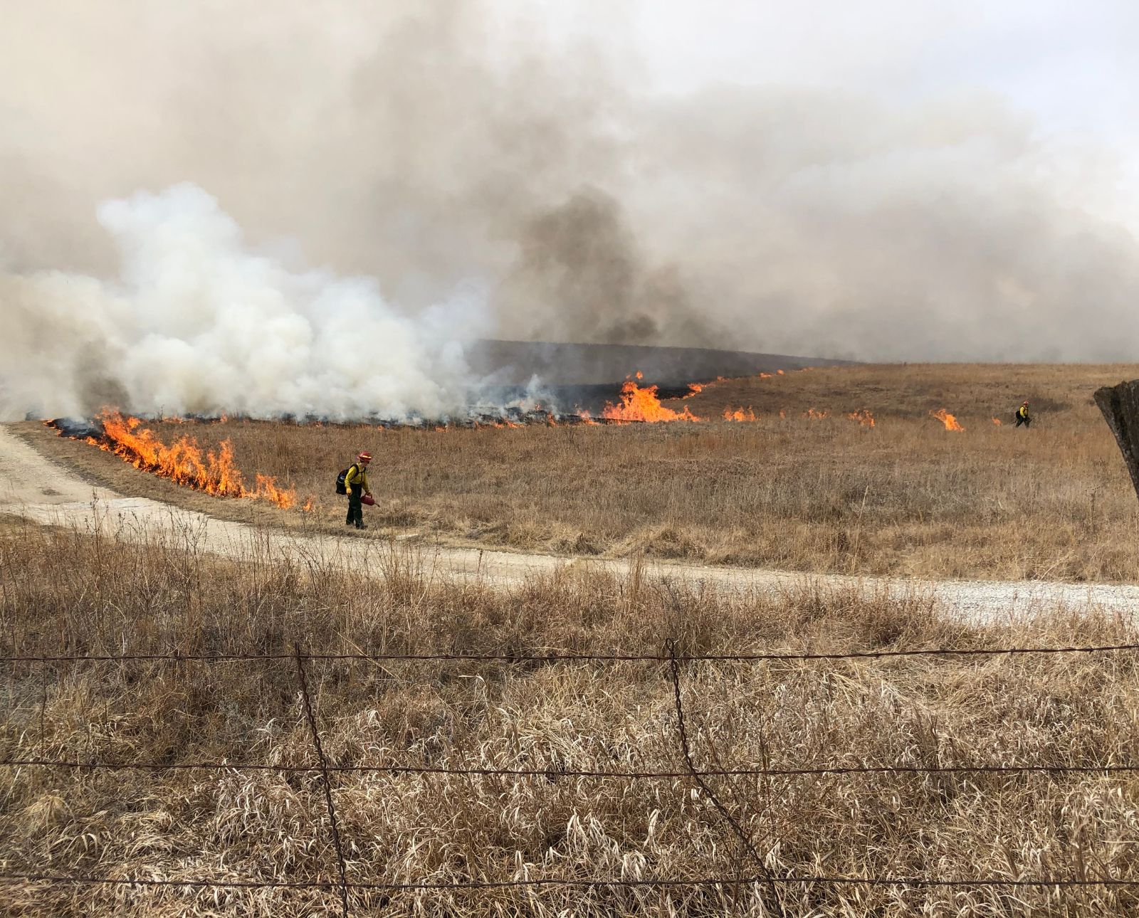 Two firefighters conducting a controlled burn at the Tallgrass Prairie National Grassland in Kansas.